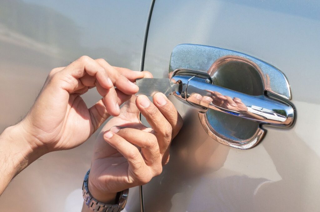 Close-up Of Person's Young Man Locksmith Hand Opening Bronze Car Door With Lock picker. Locksmith door opening device.