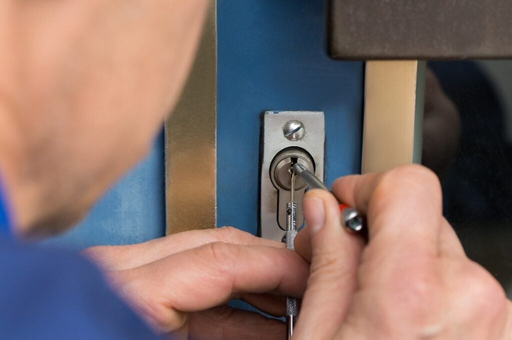 Close-up Of Male Lockpicker Fixing Door Handle At Home